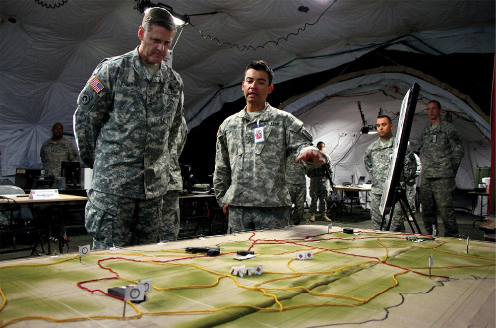 Military personnel conversing near a terrain model.